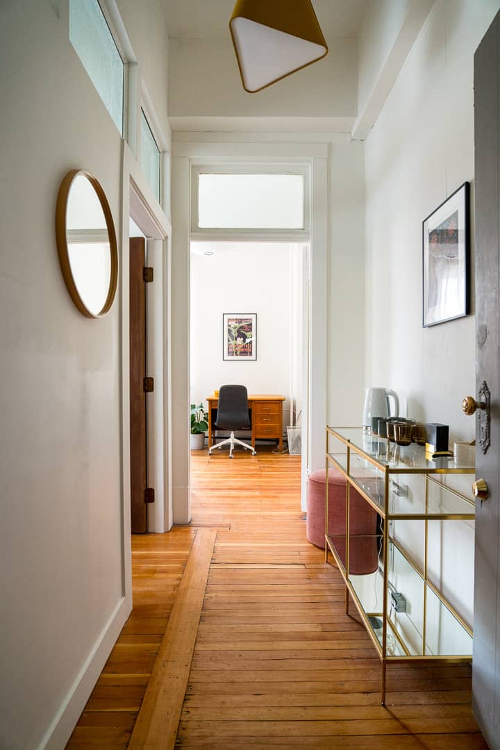 Warm and inviting hallway leading to therapy spaces at Workshop Studios, featuring a working desk.